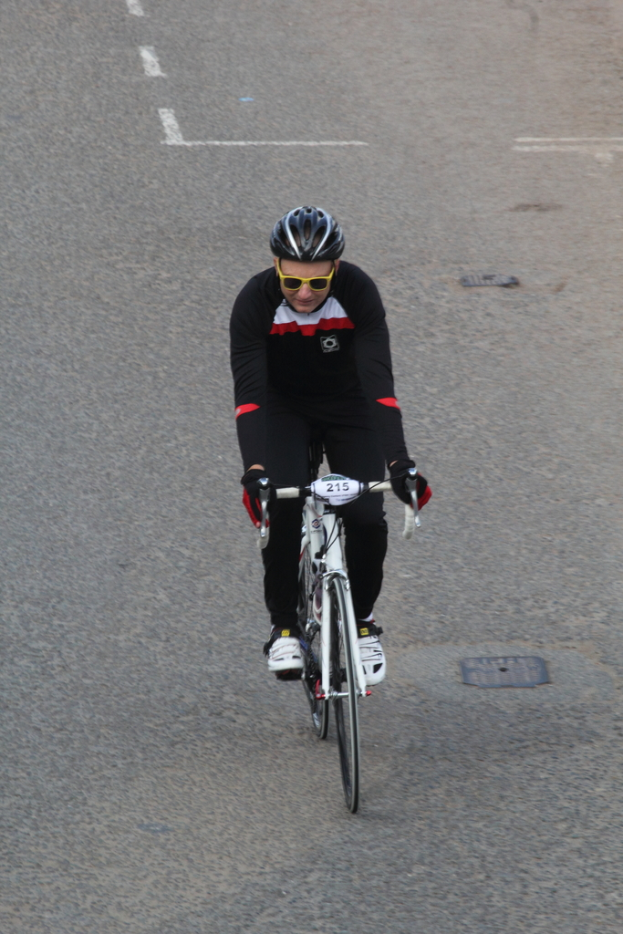Eine Person mit Helm und Brille fährt ein Fahrrad auf einer Straße.