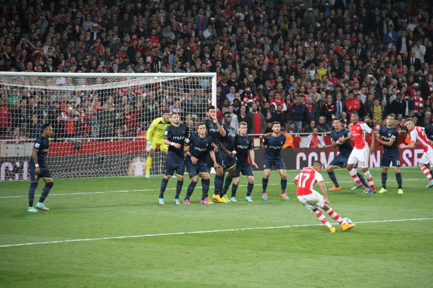 Fussballspieler auf einem Feld mit einer gro√üen Menge im Hintergrund.