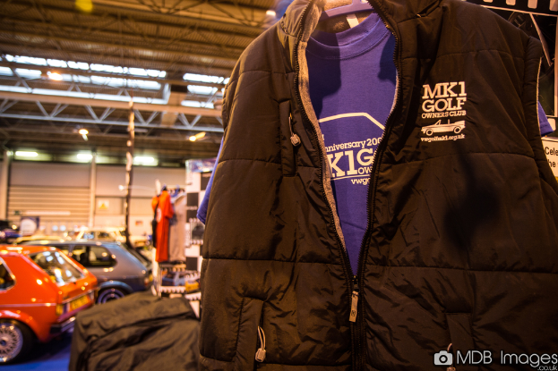 Eine Jacke ist prominent im Vordergrund zu sehen, mit Autos, Lichtern und Pfählen im Hintergrund und einer Mauer im Hintergrund.