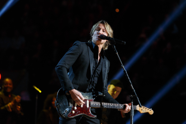 Keith Urban performs auf der Bühne im Joint im Hard Rock Hotel & Casino in Las Vegas, spielt Gitarre mit einem Mikrofon und Bandmitgliedern im Hintergrund bei gedämpftem Licht.