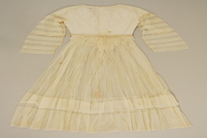 Ein weißes, langärmliges Kleid mit einer gerüschten, bodenlangen Schleppe auf einem weißen Hintergrund, mit hohem Bund und dezentem Schimmer.