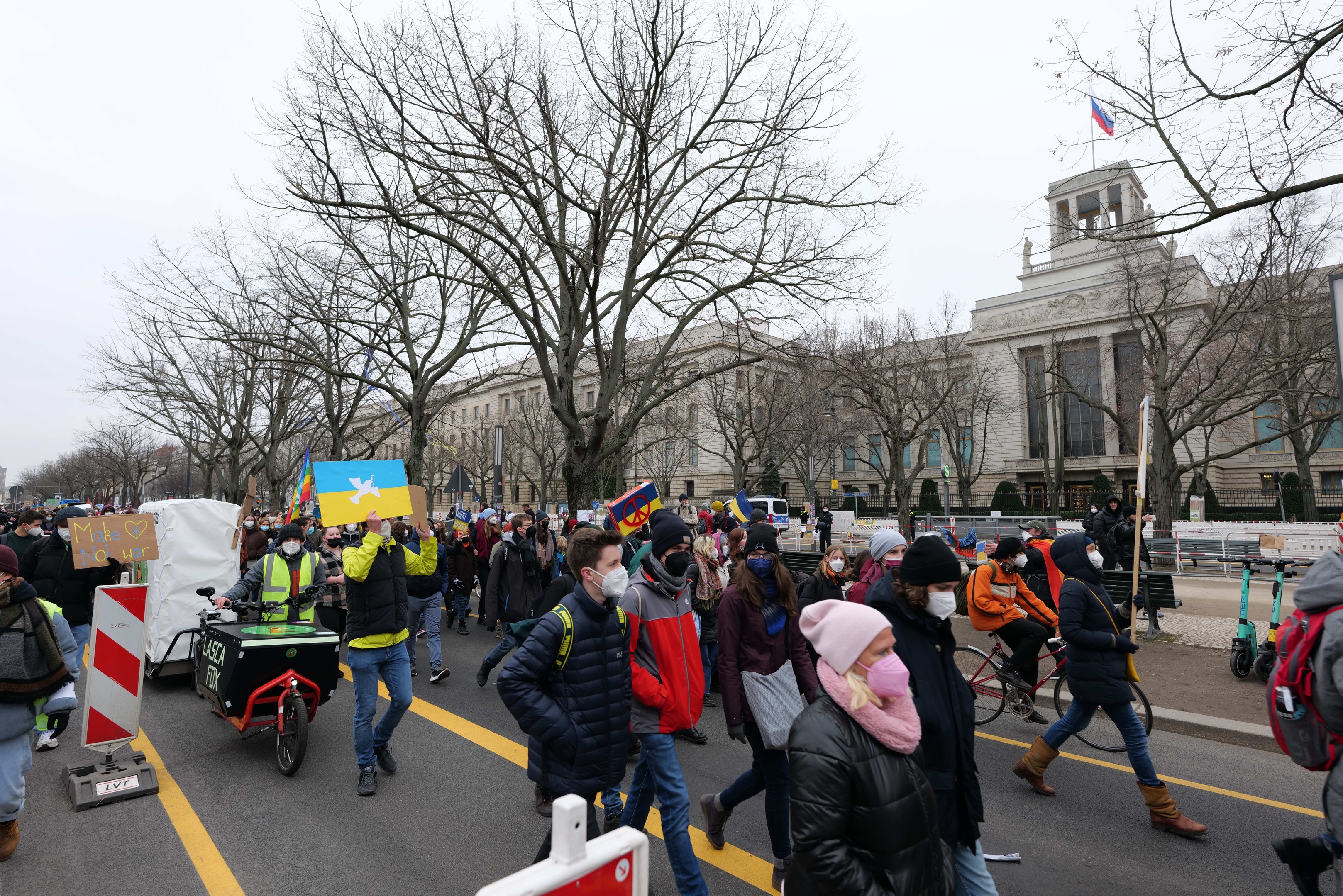 Eine große Gruppe von Menschen marschiert bei einer Demonstration in Washington, D.C., mit Schildern und Fahrrädern die Straße entlang, mit Bäumen und einem Gebäude im Hintergrund bei einem klaren blauen Himmel am 21. Januar 2020.
