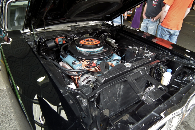 Ein Nahaufnahme von Autoteilen mit unscharfen Menschen und einer Straße im Hintergrund.