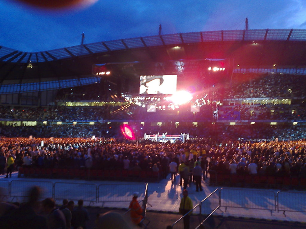 Eine Veranstaltungslokalität mit Menschen, Scheinwerfern und einem Projektionsschirm.