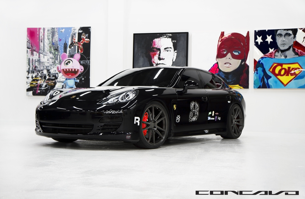 Ein schwarzer Nissan-Sportwagen parkt vor Cartoon-Postern, mit einer kleinen Inschrift am unteren Bildrand.