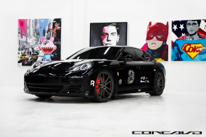 Ein schwarzer Nissan-Sportwagen parkt vor Cartoon-Postern, mit einer kleinen Inschrift am unteren Bildrand.