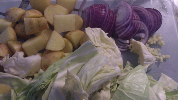 Ein Nahaufnahme von Zwiebeln, Kartoffeln und Kohlköpfen, die gemeinsam angeordnet sind.