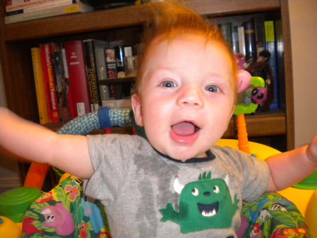 Ein Kind sitzt auf einem Stuhl vor einem teilweise sichtbaren Bücherregal mit Büchern, vor einem abgeschnittenen Wandhintergrund.