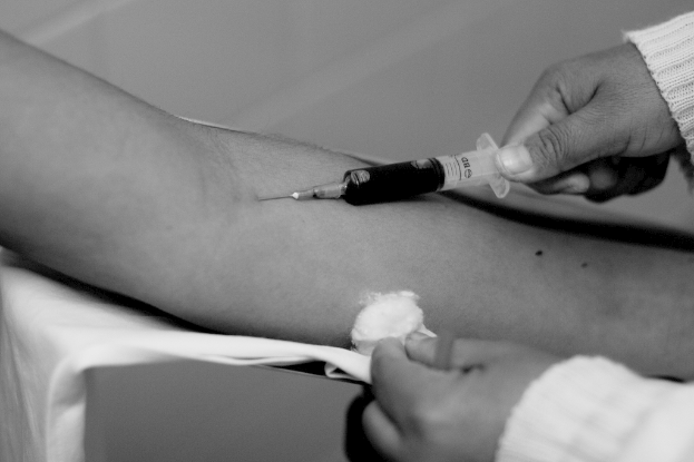 Eine Person verabreicht einer anderen Person eine Injektion in einem Schwarz-Weiß-Bild.